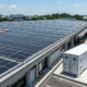 A commercial solar plus storage system featuring a 100kW BESS container next to a factory with rooftop solar panels in Europe