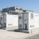 Side-by-side comparison of a 1MW and a 2MW battery storage system installed outdoors on a concrete foundation pad.
