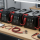 Connecting 4 12V batteries in series with heavy copper jumper cables to form a 48V battery system.