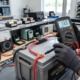 Technician measuring open-circuit resting voltage of a 12V LiFePO4 battery using a multimeter.