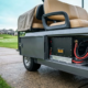 A powerful 48v 100ah lithium golf cart battery unit inside a commercial cart parked at a modern resort golf course.